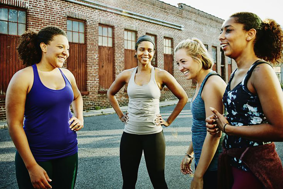 a group of diverse middle-aged women outside a gym wearing workout clothes